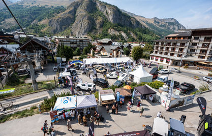 Plusieurs tentes blanches et noires dans une ville de montagne avec des gens