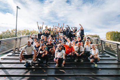 Groupe de personnes souriantes posant sur un pont, ciel bleu en arrière-plan