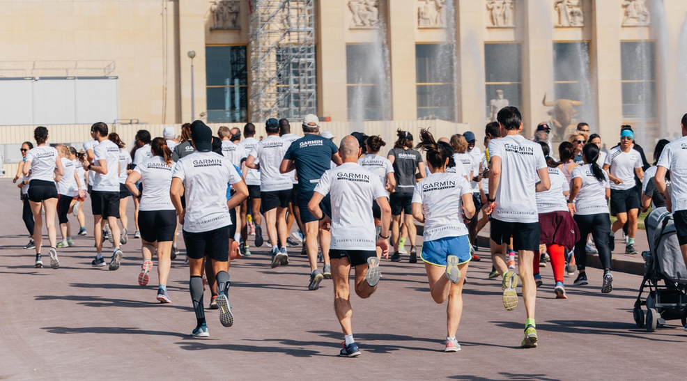 Groupe de coureurs en t-shirts blancs courant devant la fontaine et bâtiment.