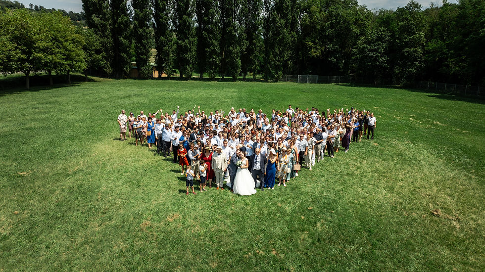 Photo de groupe en forme de cœur pour un mariage en extérieur.