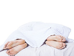 2 pairs of feet under a duvet in different directions.