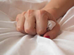 Female hand gripping the bedsheet