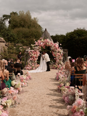 Bride and groom kiss under a gorgeous ostentatious floral arch at Kin House in Wilsthire