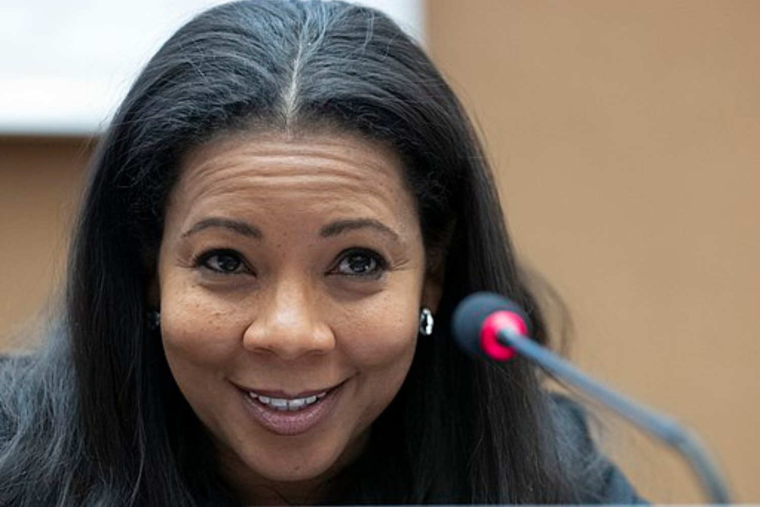 Cameroonian tech CEO Rebecca Enonchong smiling with brow raised with microphone in foreground at speaking engagement.