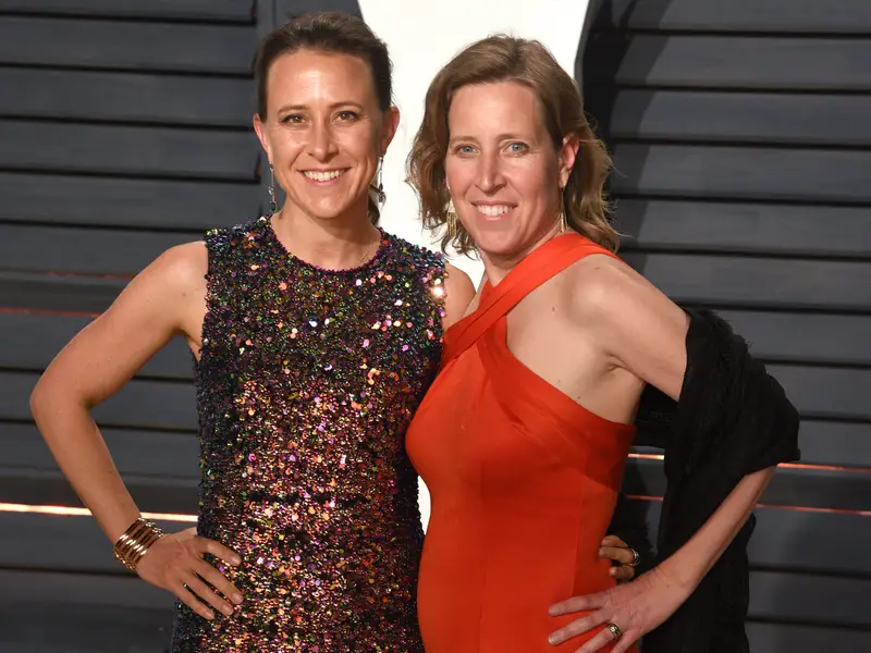 Anne and sister Suzan standing hands on hips smiling at camera wearing evening attire.