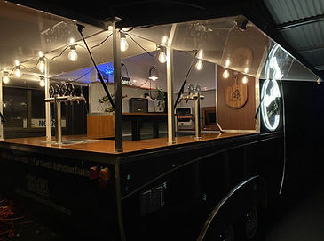 Mobile caravan bar at night with warm string lighting, multiple beer taps, and glassware setup ready for service. Ideal for outdoor bar hire events in Melbourne.