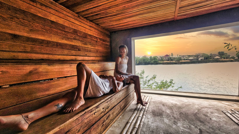 A couple enjoying a Finnish sauna overlooking a river at sunset
