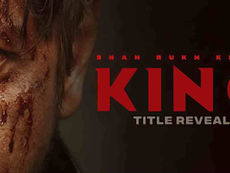 Close-up of SRK's wounded face with blood. Bold red text reads "KING" and "TITLE REVEAL." Dark background, intense mood.