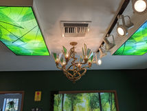 bamboo and green glass and brass whimsical forest inspired chandelier. 6 spiral arms of bamboo rings resin sealed with candelabra bulbs.
