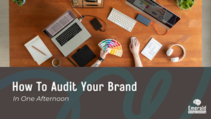 A person sitting at a desk with a laptop, computer, and cellphone working on branding elements.