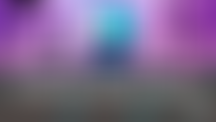 A laptop with a tablet and mobile phone on a desk with recording equipment around it and purple lighting