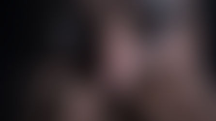 Close-up of a person's wide eyes peeking over clasped fingers in dim light, creating a tense, watchful mood.