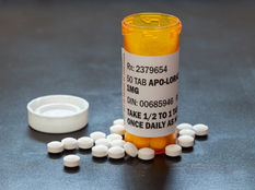Orange prescription bottle labeled for daily use with two white pills against a light blue background.