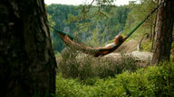 Women laying in a hammock in the forest.
