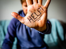 A person in a blue hoodie holds up a hand with "HELP!" written on the palm, conveying urgency and distress.