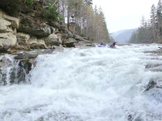 Two canoeists going over rapids and a waterfall.