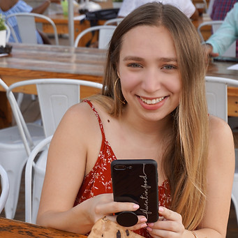 photo of founder holding phone and taking a photo of pizza fries wearing an orange shirt