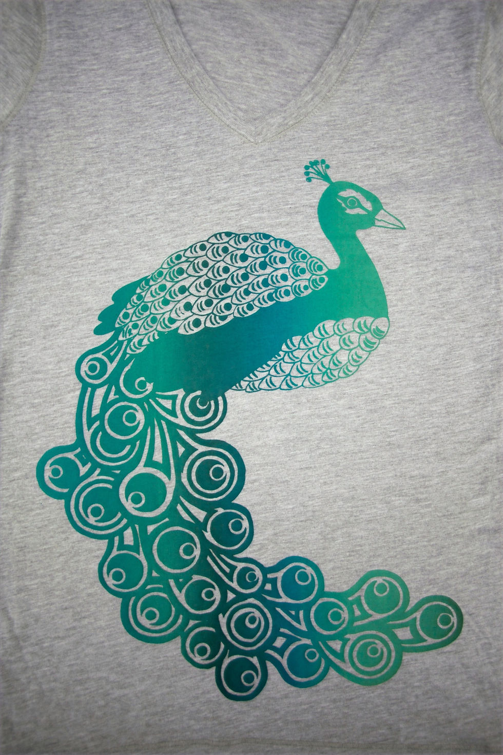 Thumbnail: Peacock printed in blues and greens on a grey v-neck - front detail