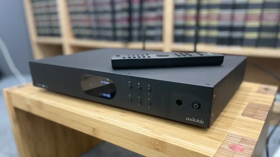 Thumbnail: Audiolab 7000N Play streamer in real-life setup on a wooden shelf, with remote control placed on top.