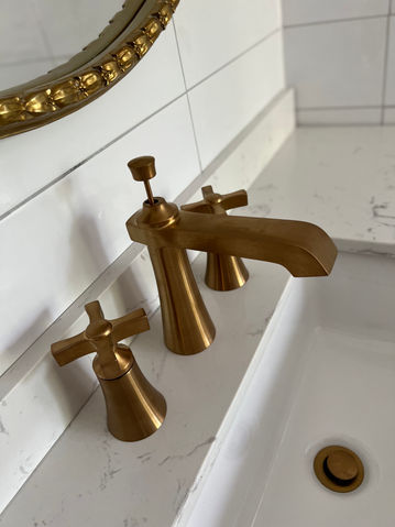 Gold faucet on a white sink with Baths for bathroom renovation project.
