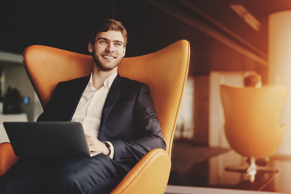 Young smiling successful man entrepreneur in formal business suite with a beard sitting on