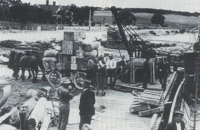 Historic black and white photo of Port Vincent wharf with workers and cargo