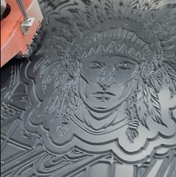Contemporary sculptural relief featuring an ancestral figure surrounded by intricate cultural patterns and illuminated architectural detailing.
