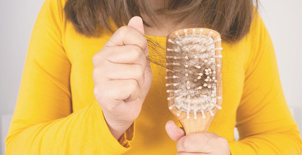 woman in yellow t shirt holding a brush and pulling tangled hair from within it