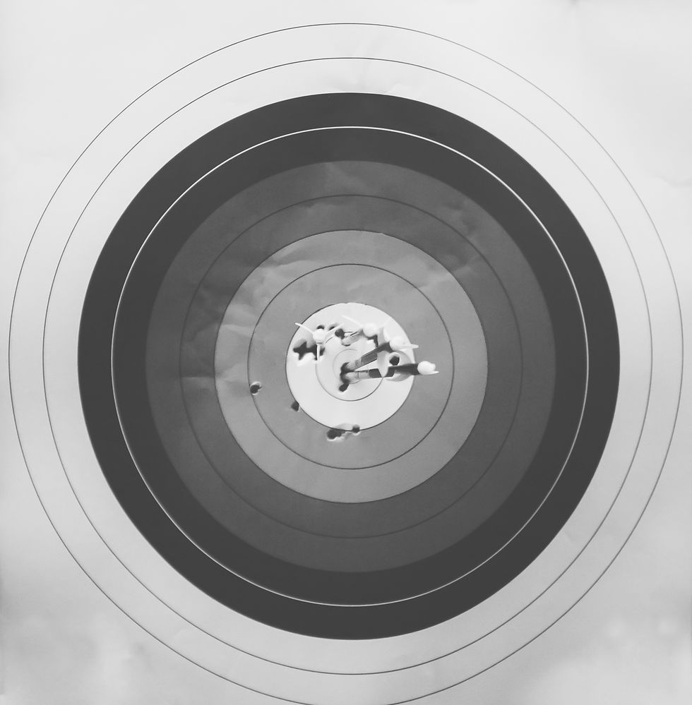 a black and white image of arrows stuck inside a round archery target.