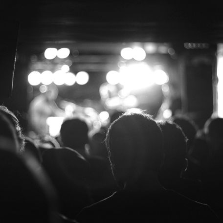 A grayscale image of an audience watching a concert stage