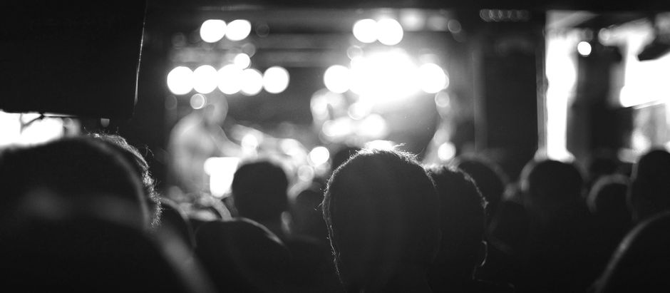A grayscale image of an audience watching a concert stage