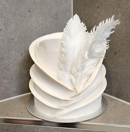 White tiered cake with feather decorations
