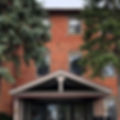 Brick three story building with glass entry way.