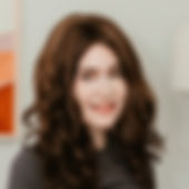 Smiling mature woman standing against dark background with arms folded across chest.