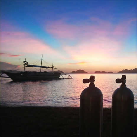 Sunset in El Nido with scuba tanks in the foreground.