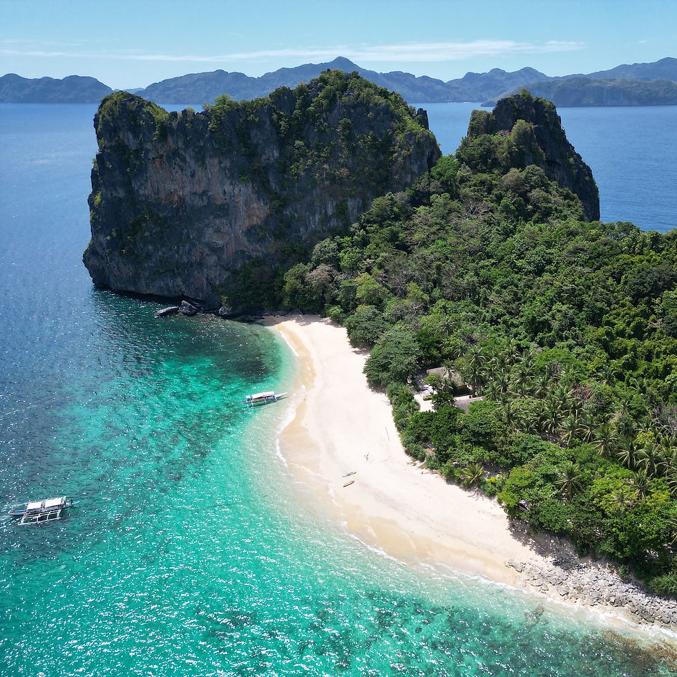 Drone view of Helicopter Island beach with boats and limestone cliffs in Bacuit Bay, El Nido