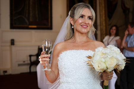 Bride drinking champagne in Windsor Guildhall after wedding ceremony.