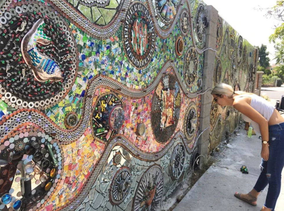 A woman looks at a wall filled with mosaic