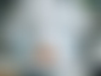 Close-up of a female doctor in a white coat with a stethoscope around her neck, writing on a clipboard in a modern medical office.