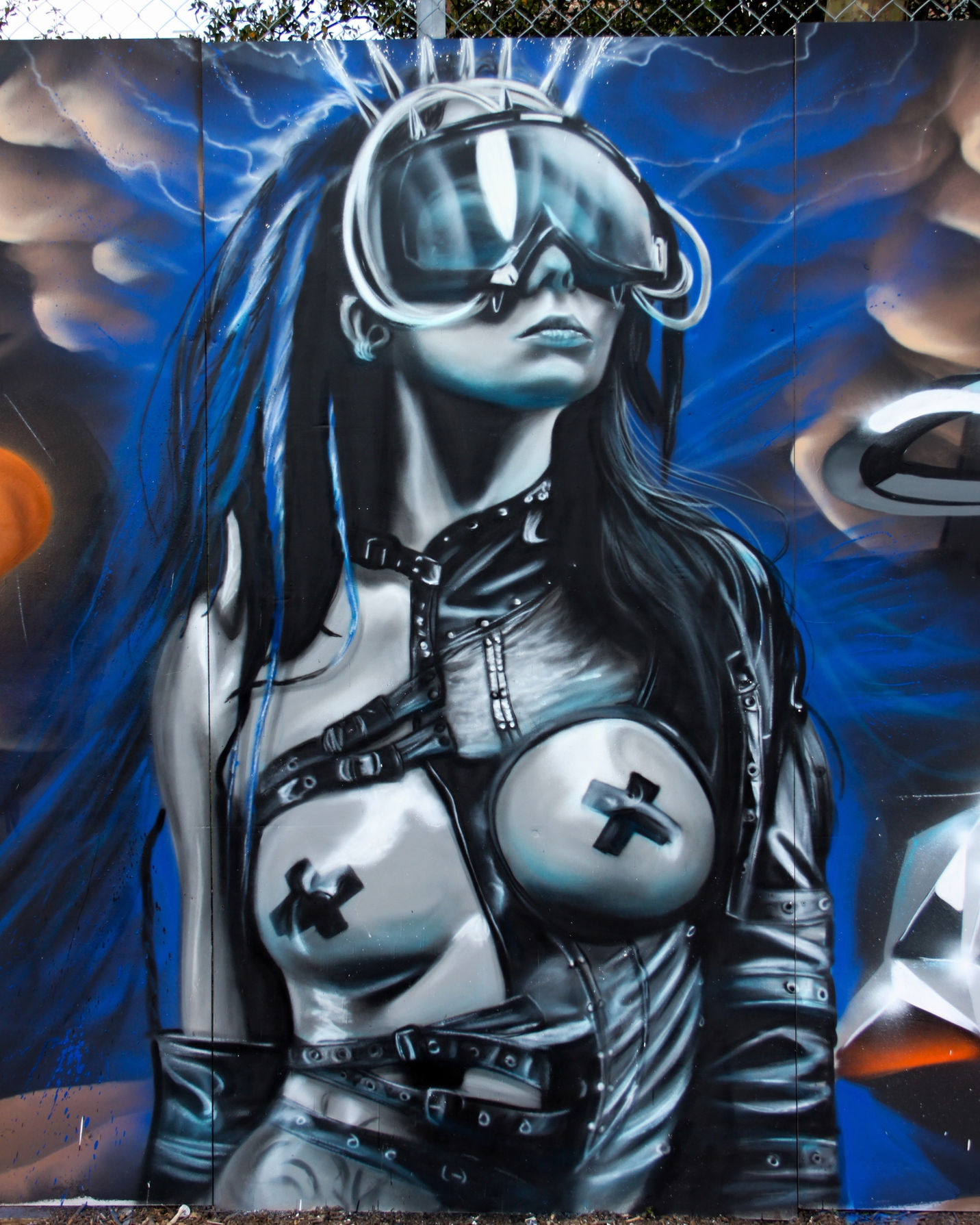 A spray painted image of a scantily clad woman wearing leather and large goggles