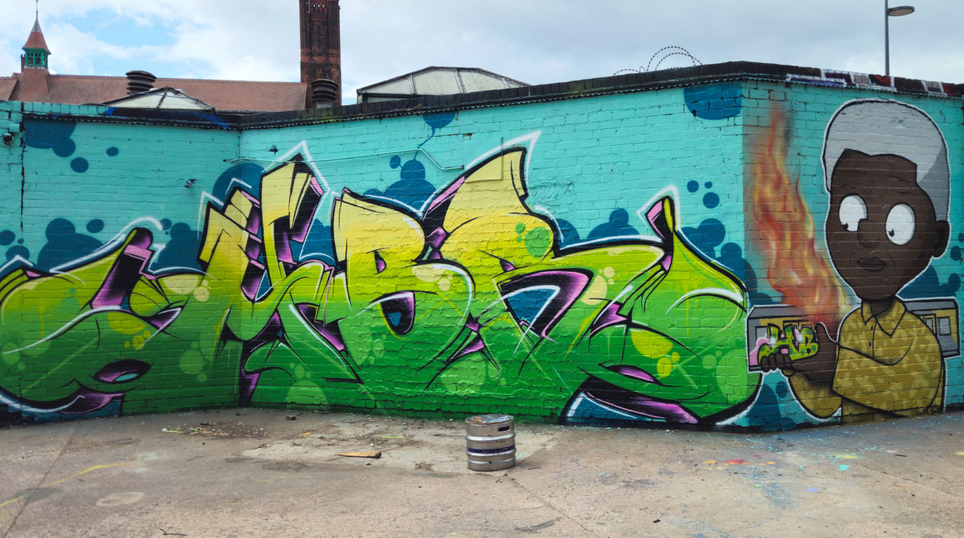 Green and yellow graffiti letters that spell out HBR next to an image of Nelson Mandela painted by Rask and Mef Remo Hated But Rated crew at The Bench504