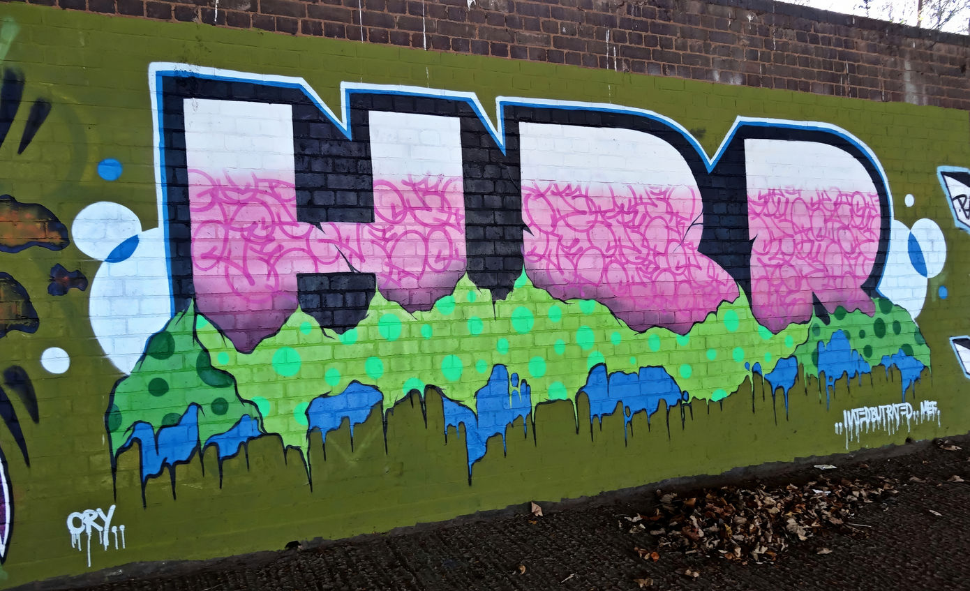 Block letter graffiti wall that uses the colours pink, green, blue and white painted by writer artist Mef Remo HBR Hated But Rated crew