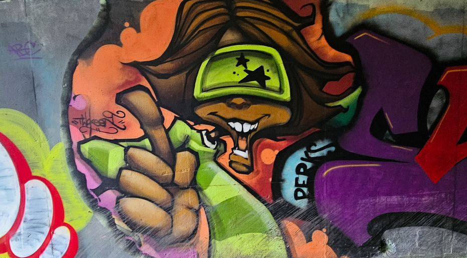 A graffiti character wearing sunglasses and pointing at you
