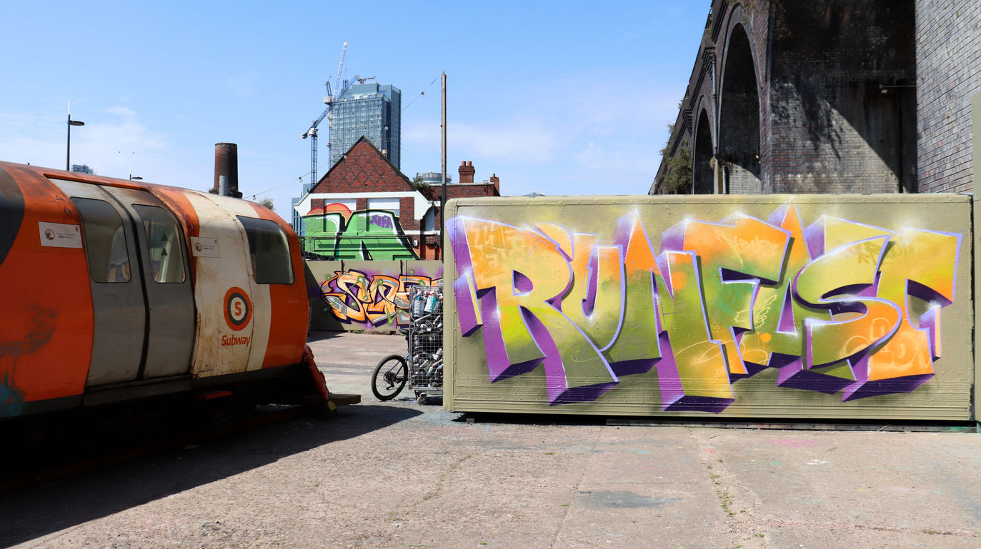 Graffiti letters that say Runfast spray painted next to a train