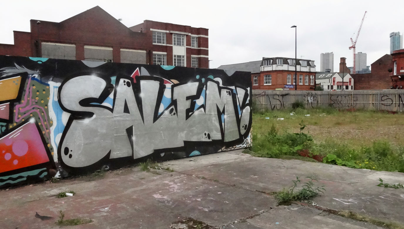 Silver coloured graffiti lettering, painted onto some boards, on some abandoned waste land by writer artist Salem