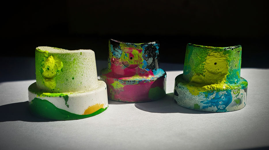 Three paint covered caps from graffiti spray cans