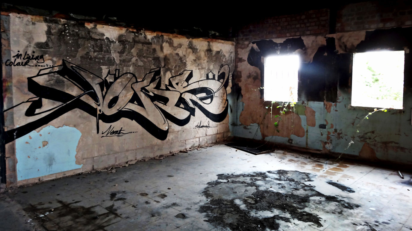 Graffiti lettering in a dark, and moody looking, abandoned building