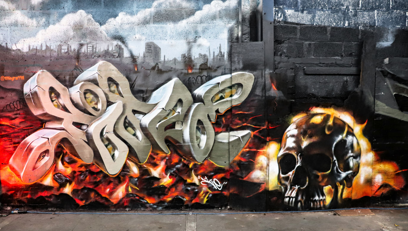 Graffiti lettering that says "Title" with a very realistic burning skull spray painted next to it by writer artist Title