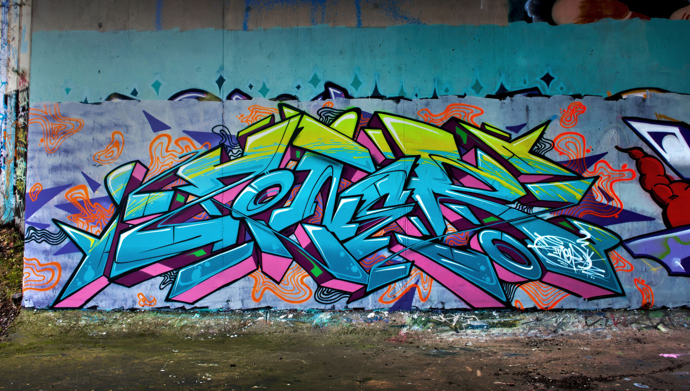 A very vibrant coloured piece of graffiti painted under an old bridge