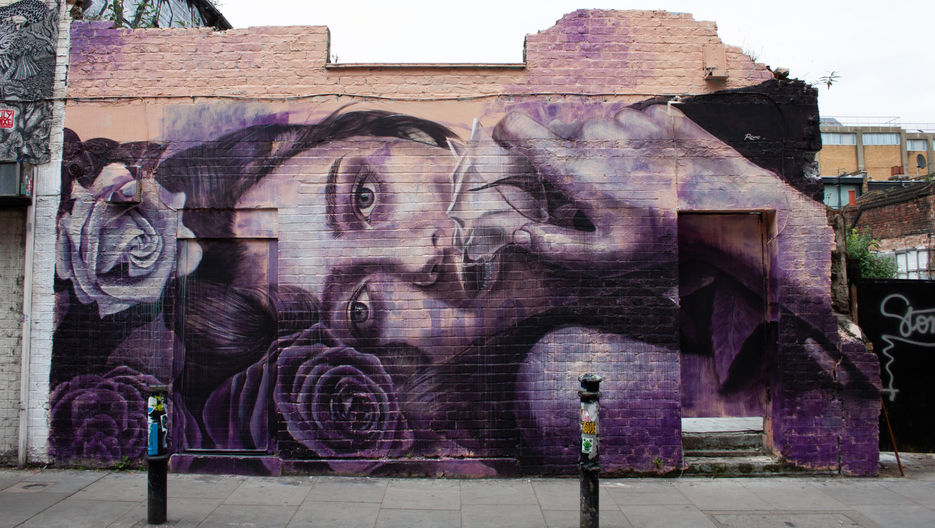 A piece of street art showing a lady lying on her side surrounded by flowers